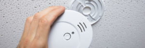 Person cleaning a smoke detector on the wall