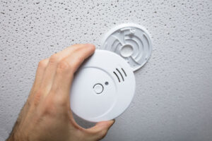 Person cleaning a smoke detector on the wall