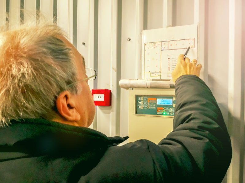Engineer inspecting fire alarm panel