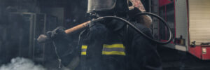 Portrait of a fireman wearing firefighter turnouts holding a rescue axe before he fights commercial fire.