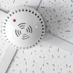 Modern smoke detector on commercial ceiling indoors